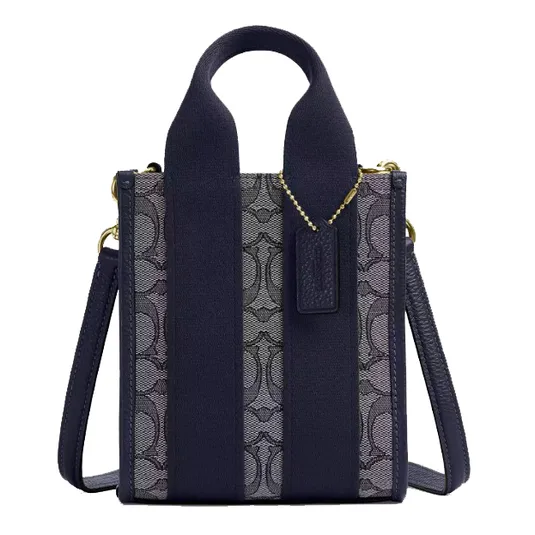 A compact handbag with a navy-blue color scheme, featuring a patterned fabric on the front, wide handles, a detachable shoulder strap, and gold hardware.