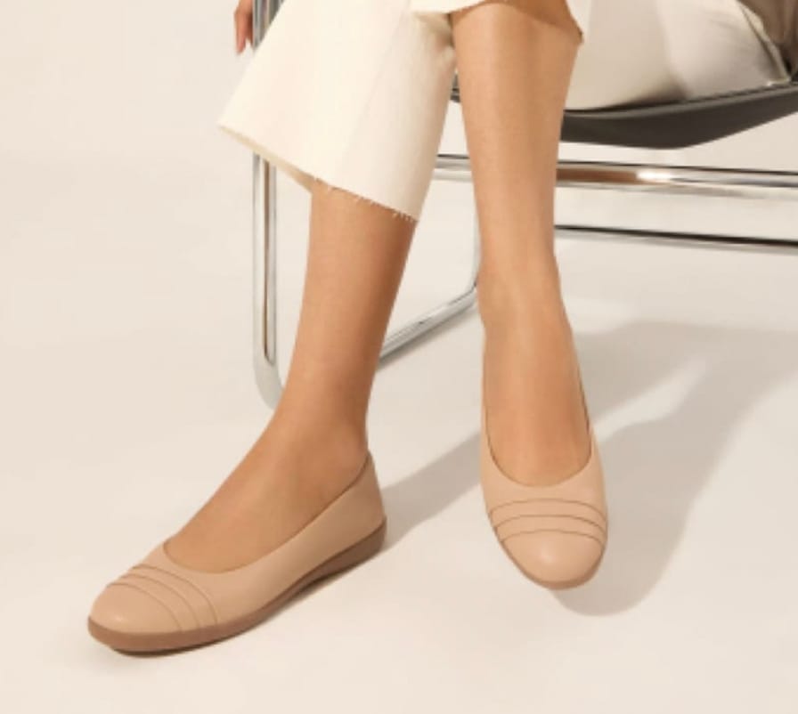 A pair of beige ballet flats on a person's feet.