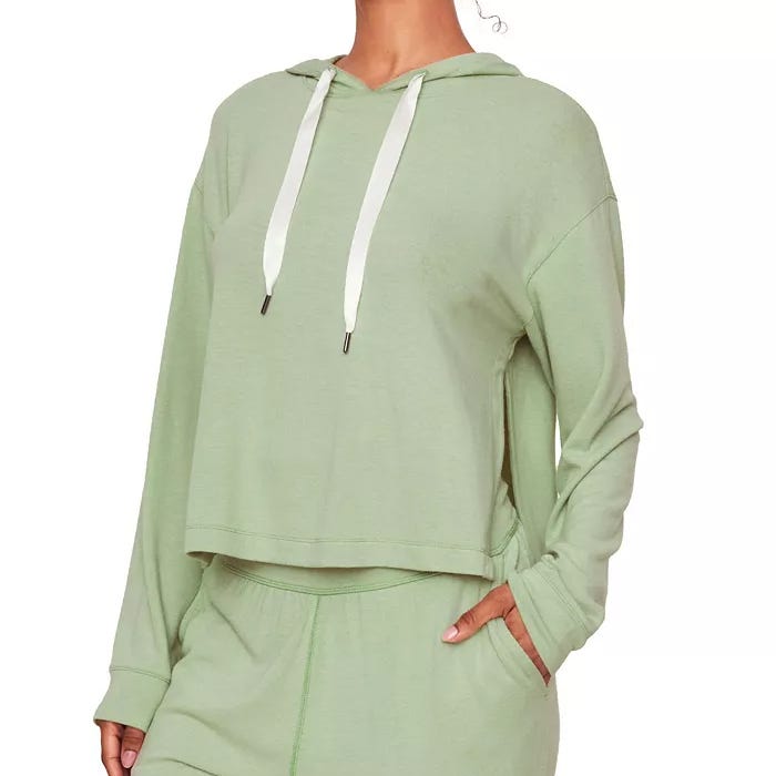 A person wearing a pale green cropped hoodie with white drawstrings.