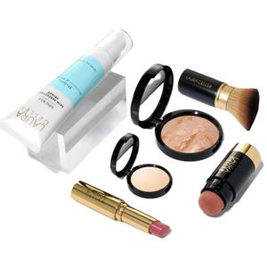 The 6pc Laura Geller New Icons Kit includes a resurfacing serum, kabuki brush, baked blush, compact powder, a pink lipstick, and a highlighting stick.