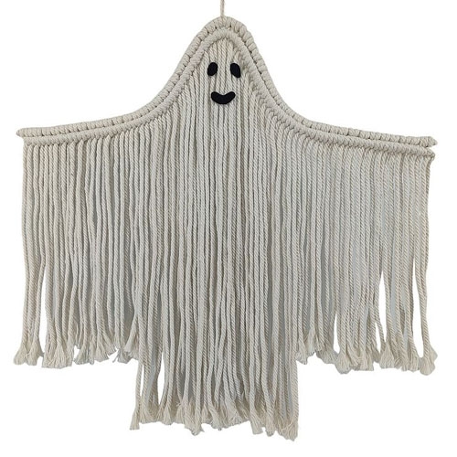 A macramé wall hanging shaped like a ghost, made with white rope and featuring a smiling face.