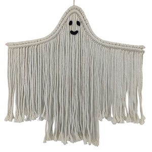 A macramé wall hanging shaped like a ghost, made with white rope and featuring a smiling face.