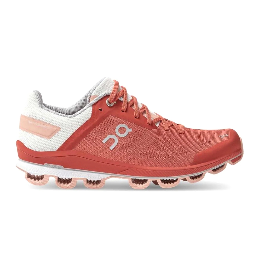Running shoe with a coral and white color scheme, featuring a distinctive sole design with circular elements; branding is visible on the side.