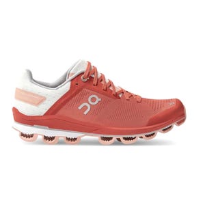 Running shoe with a coral and white color scheme, featuring a distinctive sole design with circular elements; branding is visible on the side.