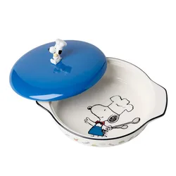 A round ceramic casserole dish featuring a blue lid with a decorative figure of a dog wearing a chef's hat. The dish's interior and exterior are adorned with illustrations of the same dog cooking.