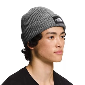 The North Face Lined Beanie is a gray, ribbed knit hat with a folded cuff, featuring a black and white logo patch on the front.