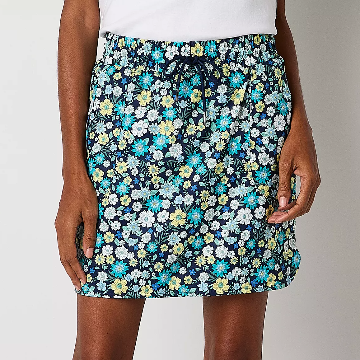 A floral print skirt with a drawstring waist, featuring blue, yellow, and white flowers on a black background.