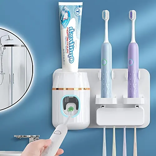 A wall-mounted toothpaste dispenser with an automatic squeezer and storage slots for multiple toothbrushes. The device is paired with a tube of toothpaste and two electric toothbrushes.