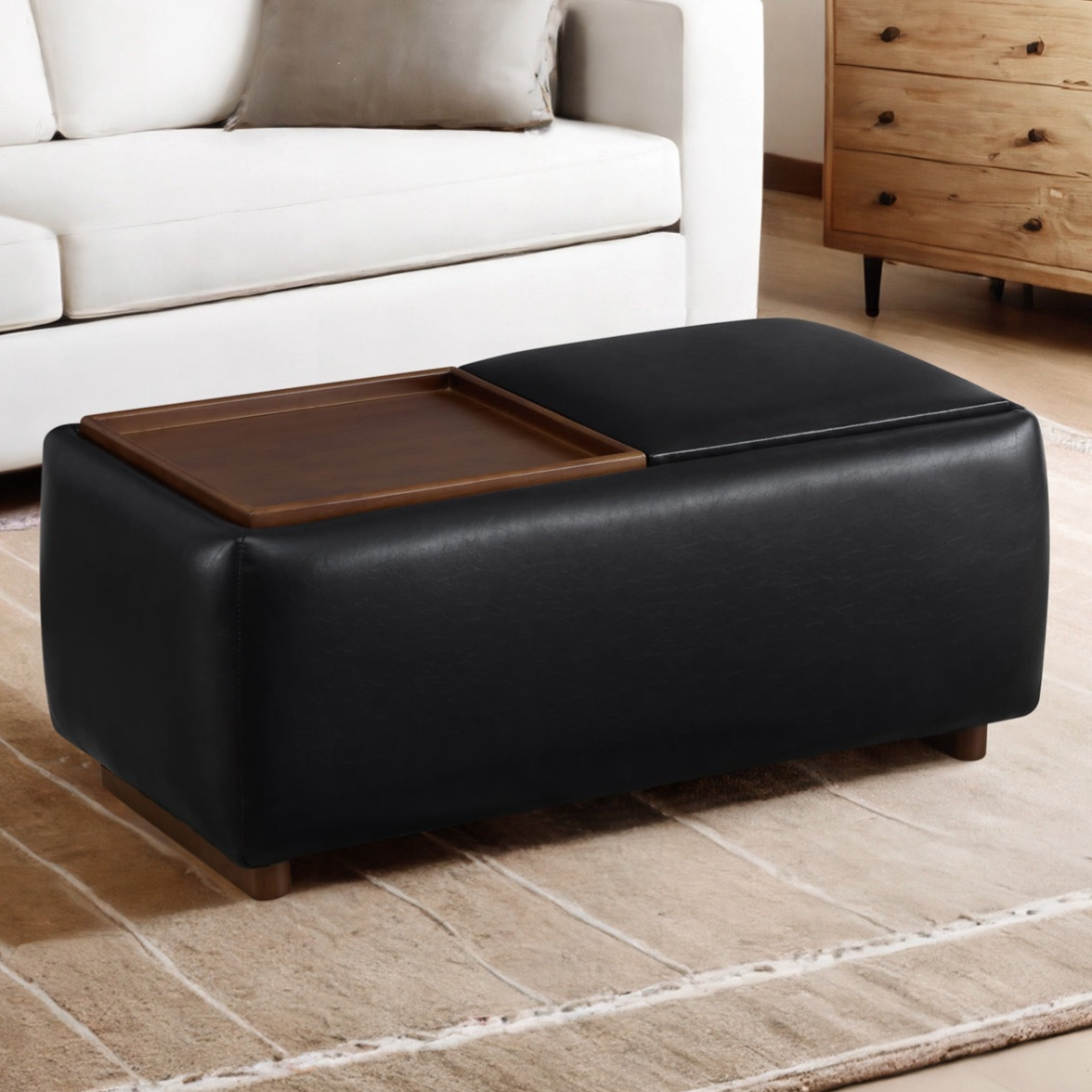 Black rectangular ottoman with a wooden tray on top, placed in a living room setting featuring a white sofa and a wooden dresser.