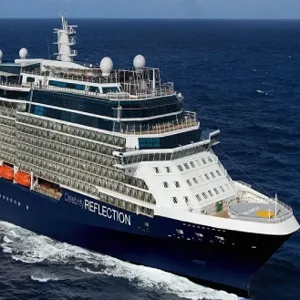 A large cruise ship named Celebrity Reflection is sailing on the ocean, featuring multiple decks, balconies, and visible lifeboats.
