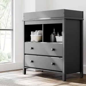 Gray changing table with two drawers and open shelves, featuring a basket with diapers and bottles.