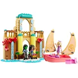 A colorful castle playset with an accompanying sailboat includes three mini-figurines, one using a wheelchair, and detailed architecture featuring flowers and ornate designs.