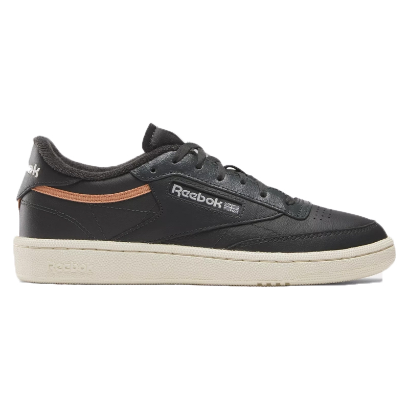 The Reebok Club C Vintage Shoes feature a black leather upper with a retro design, accented by a subtle orange stripe and classic branding on the side. They have a contrasting beige sole for a timeless, casual look.