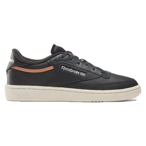 The Reebok Club C Vintage Shoes feature a black leather upper with a retro design, accented by a subtle orange stripe and classic branding on the side. They have a contrasting beige sole for a timeless, casual look.