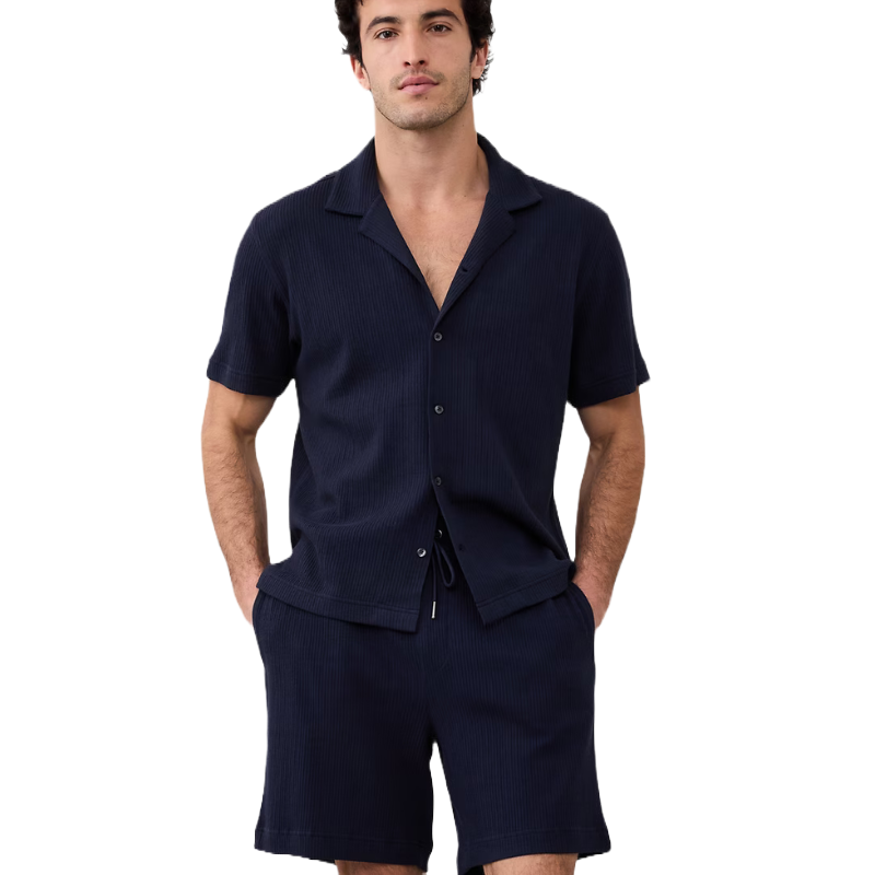 Man wearing a navy short-sleeve button-up shirt and matching shorts, both with a subtle textured pattern.