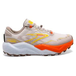 Brooks Caldera 7 Trail Shoes feature a beige upper with orange and yellow accents, a thick white and orange midsole for cushioning, and a durable brown outsole. Designed for trail running, they offer support and grip on various terrains.