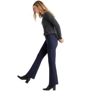 A woman is wearing a grey sweater, navy flared trousers, and black heeled boots.