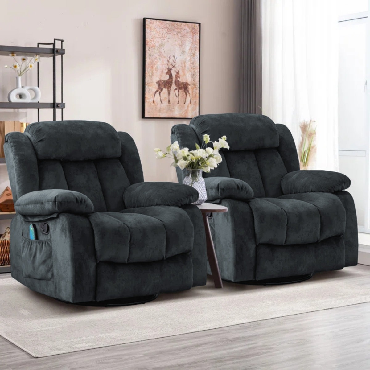 Two plush, dark gray recliners with padded armrests and a side pocket, placed in a living room setting with a small table between them and a deer artwork above.
