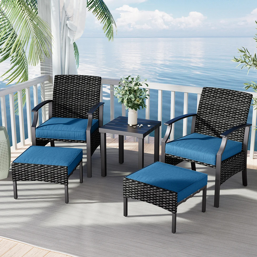 Outdoor furniture set with two chairs, cushions, a loveseat, and a coffee table on a balcony overlooking the sea.