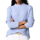 A person wearing a light blue knit sweater with a crew neckline, paired with white pants and a gold belt.
