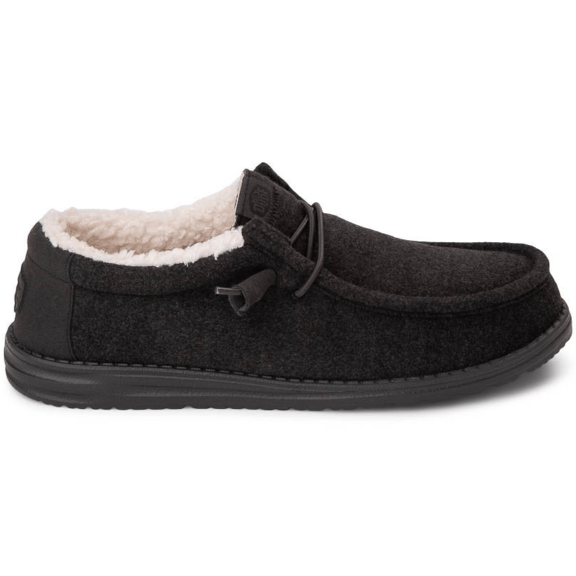 A black slip-on shoe with a soft, fleecy interior lining, featuring a moccasin-style upper and a flexible sole with minimal detailing.