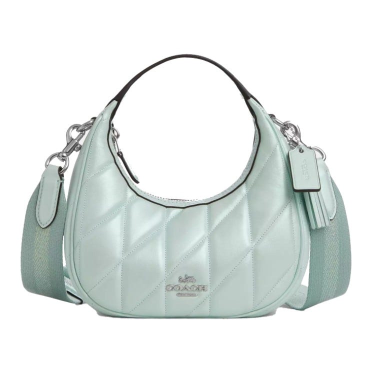 A light green quilted Coach handbag with silver hardware, featuring a top handle and a detachable strap.