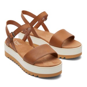 Brown platform sandals with a wide strap, adjustable ankle buckle, and white sole.