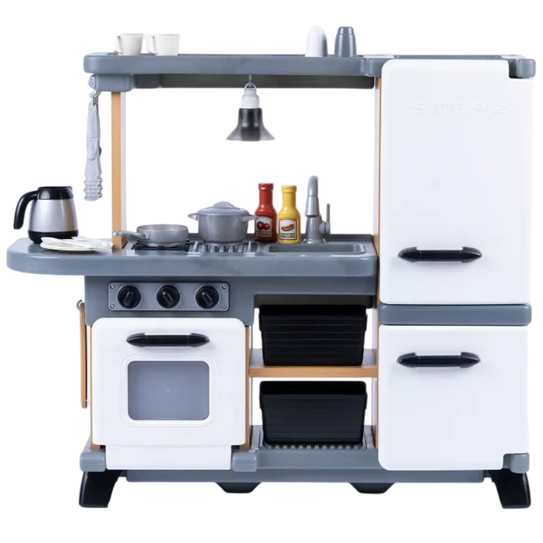 Toy kitchen set with a stove, oven, sink, and refrigerator, featuring accessories like a coffee pot, sauce bottles, and cookware.