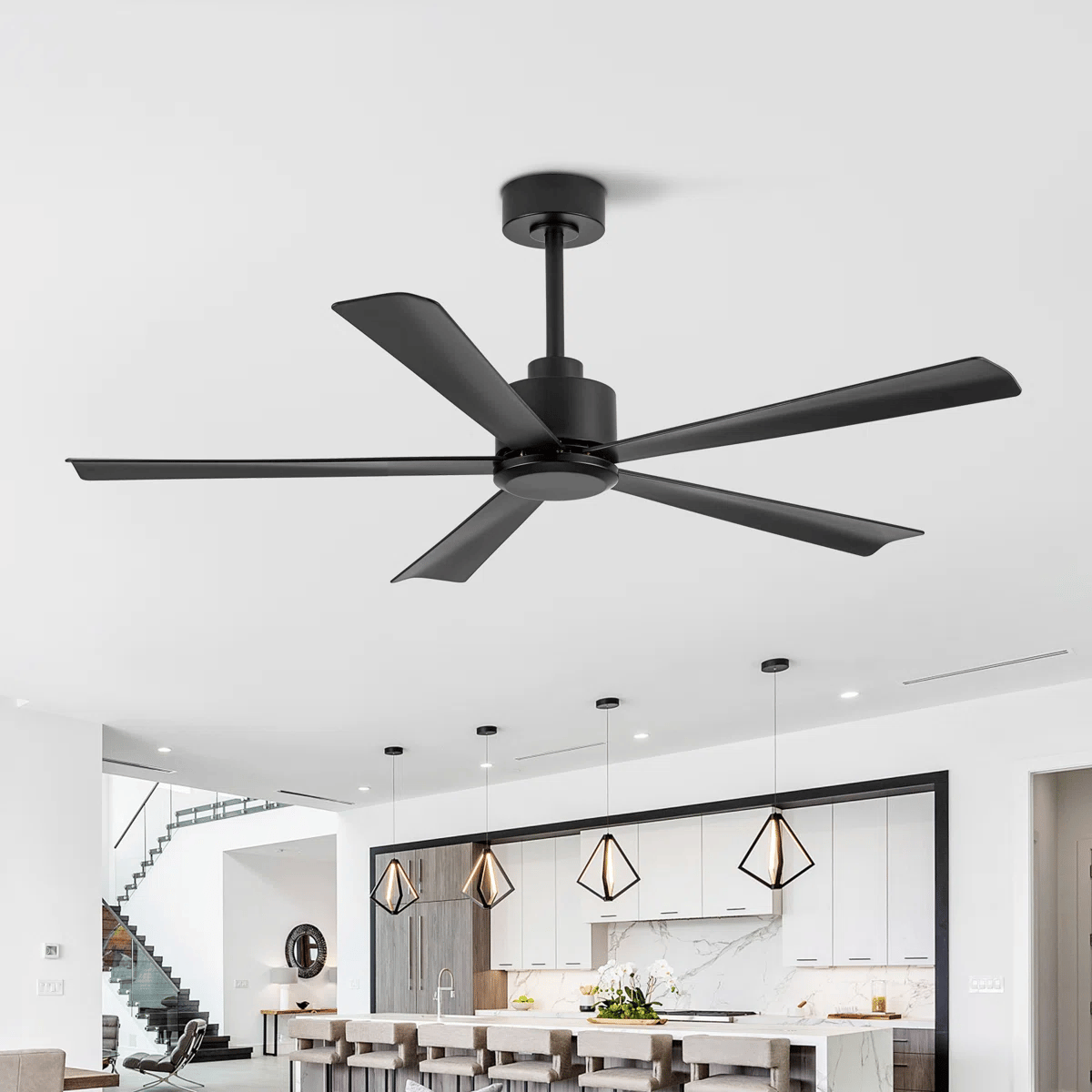 A modern black ceiling fan with five blades installed in a contemporary kitchen setting, featuring pendant lights and sleek cabinetry.