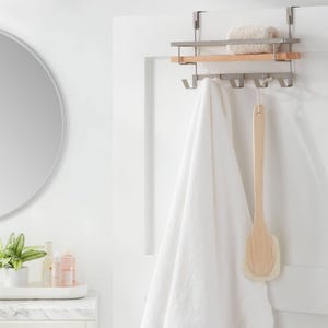 Over-the-door rack shelf with a sleek metal design, featuring a wooden accent, multiple hooks for hanging items, and space on top for storage. Ideal for holding towels and bath accessories.