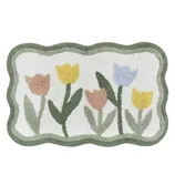 A rectangular rug with a scalloped border features a design of pastel tulips in yellow, blue, and pink on a white background.