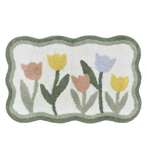 A rectangular rug with a scalloped border features a design of pastel tulips in yellow, blue, and pink on a white background.