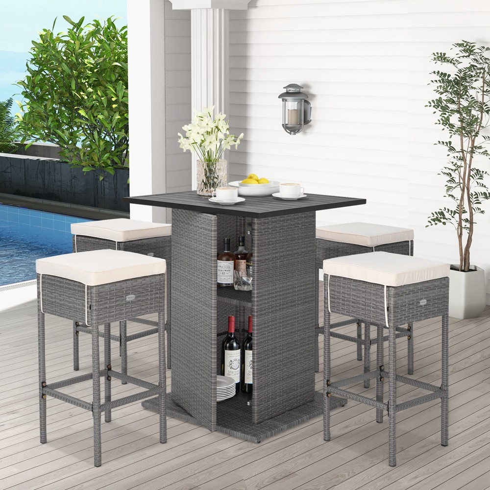 A wicker outdoor bar set with a high table and storage shelves, accompanied by two bar stools with light cushions.