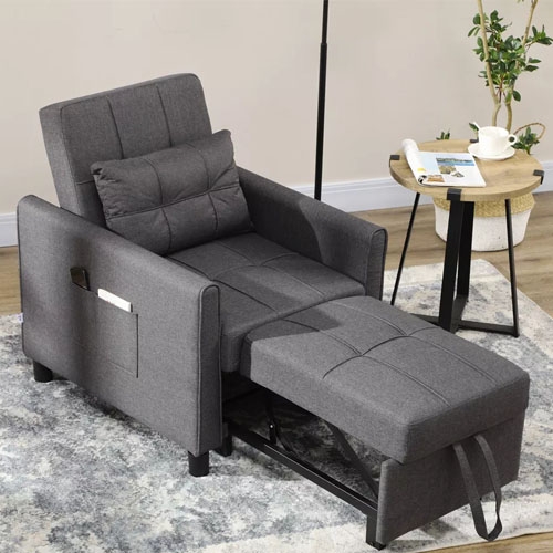 A gray recliner chair with extended footrest, side pocket, and a matching cushion, next to a small round side table with a plant and teacup.