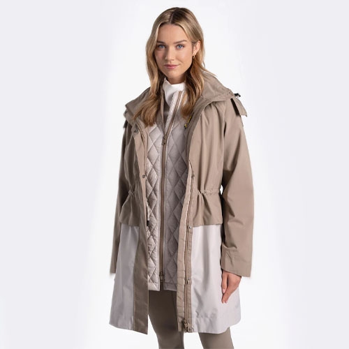 A woman modeling a layered beige raincoat with quilted lining and hood.