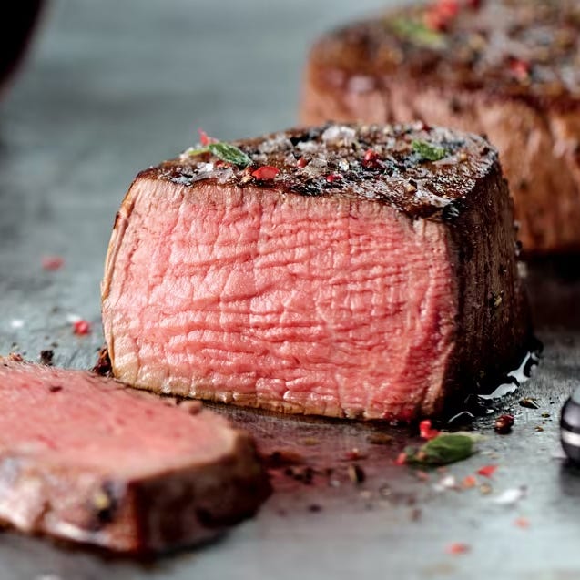 A medium-rare steak is seasoned and garnished with herbs and spices, showcasing a juicy, tender texture.
