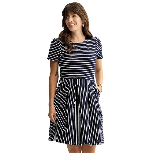 A woman is wearing a navy and white striped dress with short sleeves and a pleated skirt. The dress has a fitted bodice and appears to have pockets.