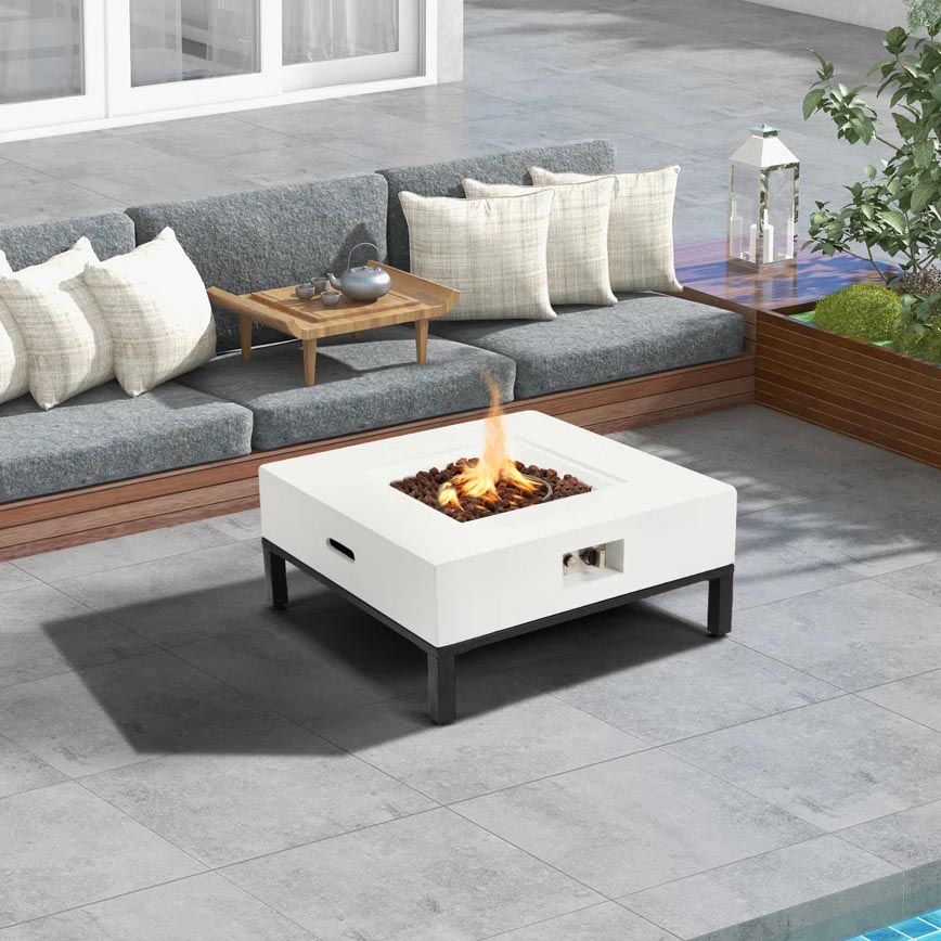 Outdoor patio setup with a gray cushioned L-shaped sofa, white fire pit table with black legs and built-in handle, and a small wooden tray table.