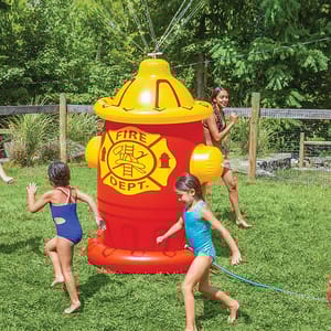 An oversized inflatable fire hydrant sprinkler with a \“Fire Dept.\“ logo that sprays water from the top, set in a grassy yard with children playing around it in swimsuits.