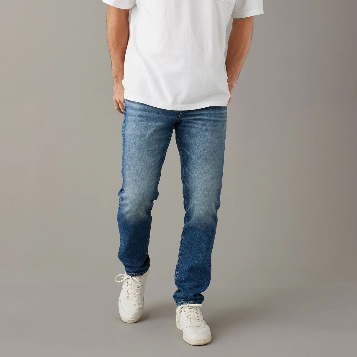 A person wearing a white t-shirt, blue jeans, and white sneakers.