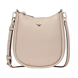 A beige leather crossbody bag with a gold spade logo, featuring an adjustable strap and gold hardware.