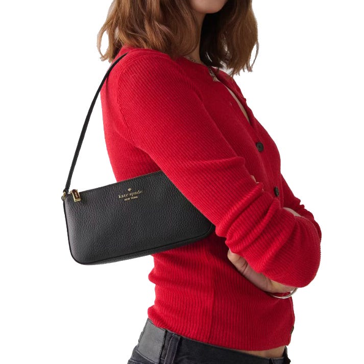 A person is wearing a red ribbed cardigan and carrying a small black Kate Spade New York handbag on their shoulder.
