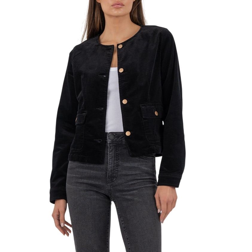 A woman is wearing a black velvet button-up jacket over a white top, paired with high-waisted dark gray jeans and black pointed-toe heels.
