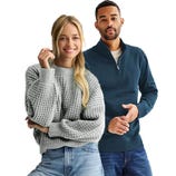 Two individuals are wearing casual sweaters; one is in a chunky gray knit sweater and jeans, while the other is in a dark blue zip-neck sweater and jeans.