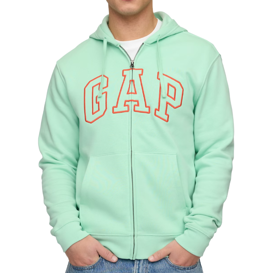 A person is wearing a mint green zip-up hoodie with \“GAP\“ in red outlined letters. It is paired with light blue jeans.