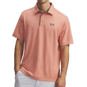 A light pink short-sleeve polo shirt featuring the Under Armour logo on the chest, paired with white pants.