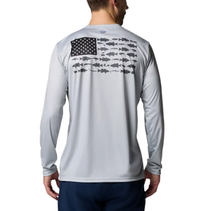 A person is wearing a light grey long-sleeve shirt with a design of an American flag, where the stripes are composed of various fish silhouettes, paired with dark pants.