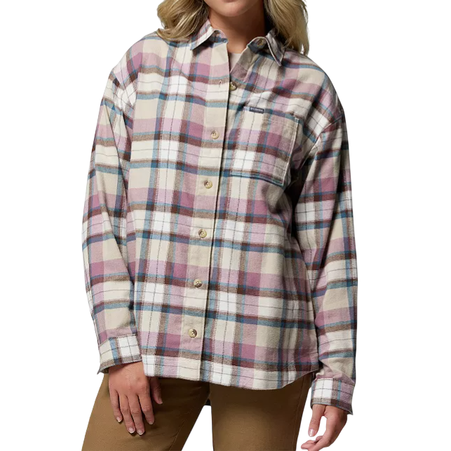 A blonde woman wears a plaid button-up shirt with a checkered pattern in muted tones of pink, cream, and blue. She pairs it with tan pants, creating a casual and stylish look.