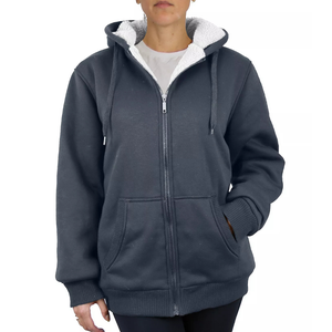 A person wearing a dark blue zip-up hoodie with a white fleece-lined hood and front pockets.