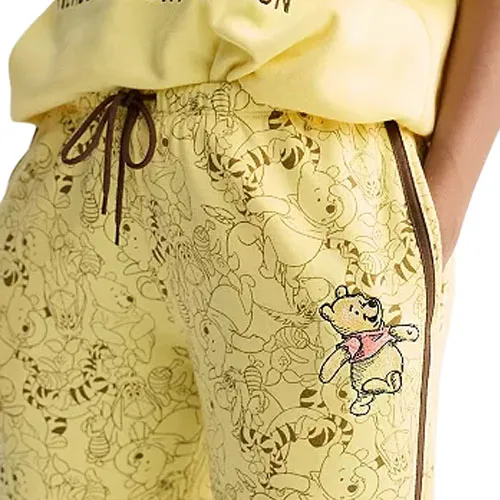 Yellow sweatpants with a drawstring and a pattern featuring a bear and friends, with a larger embroidered bear on the side.